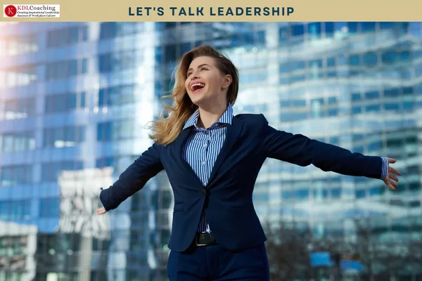 Confident businesswoman with her arms outstretched in front of city office towers
