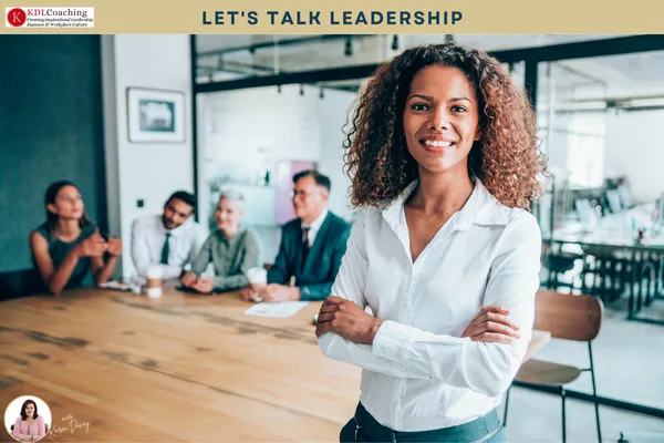 Confident woman with her arms folded in front of her team at a meeting table