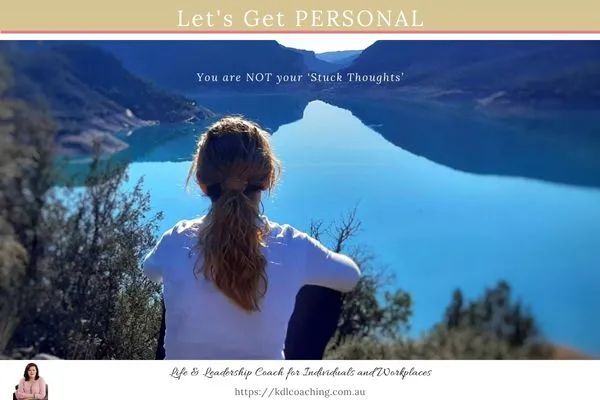 Woman sitting on a hillside looking out over a mountain lake, with the words: You are not your stuck thoughts
