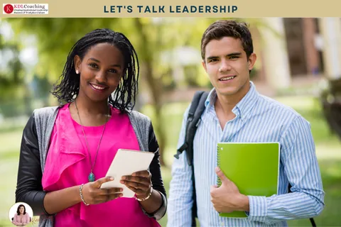 Two young professionals smiling and holding notebooks