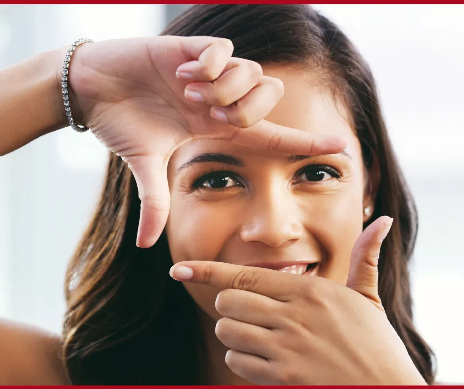 Smiling woman framing her face with her fingers, seeing things from a new angle